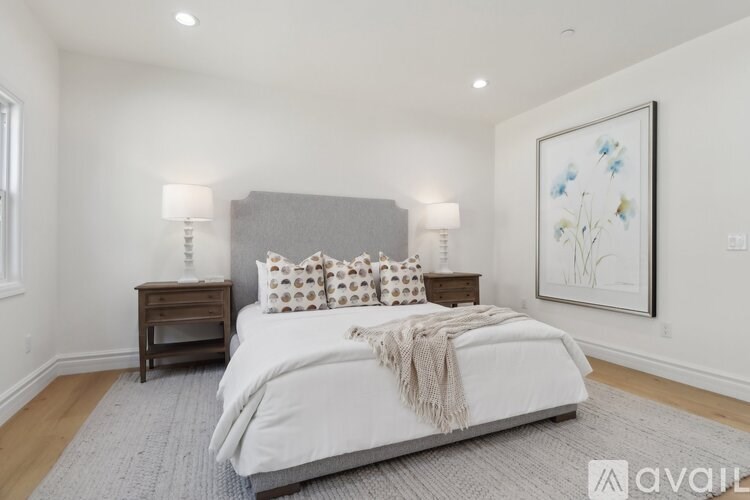 A bedroom with a large bed and a painting on the wall.