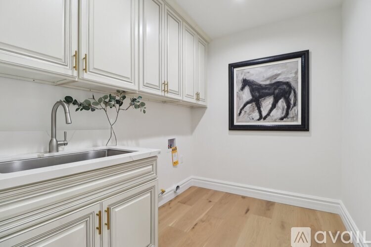 A kitchen with white cabinets and a framed picture of a horse on the wall.