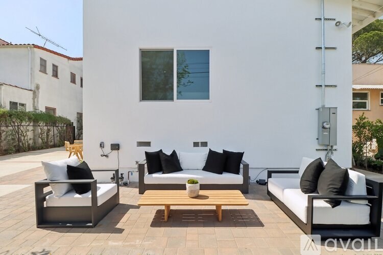 A white patio with a couch, chairs, and a table.