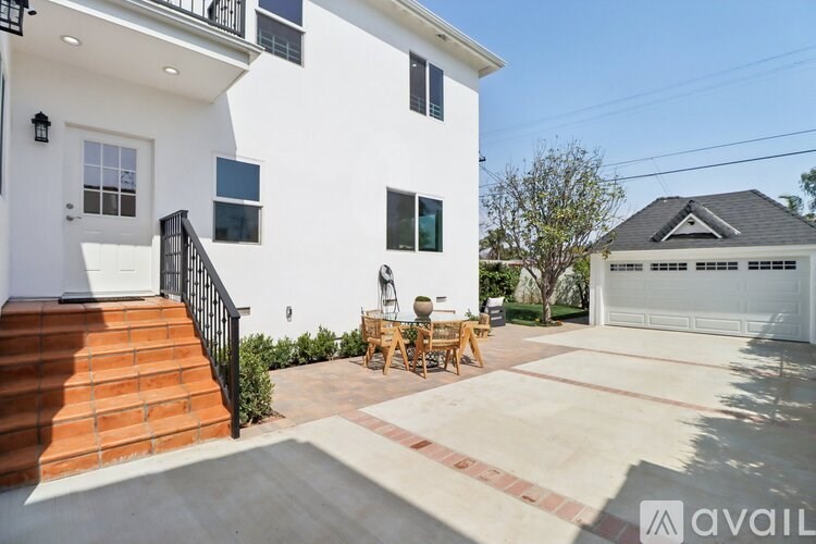 A white two-story house with a black railing on the stairs.