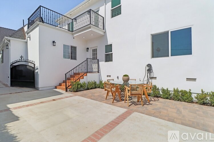 A white house with a black gate and a patio with a table and chairs.