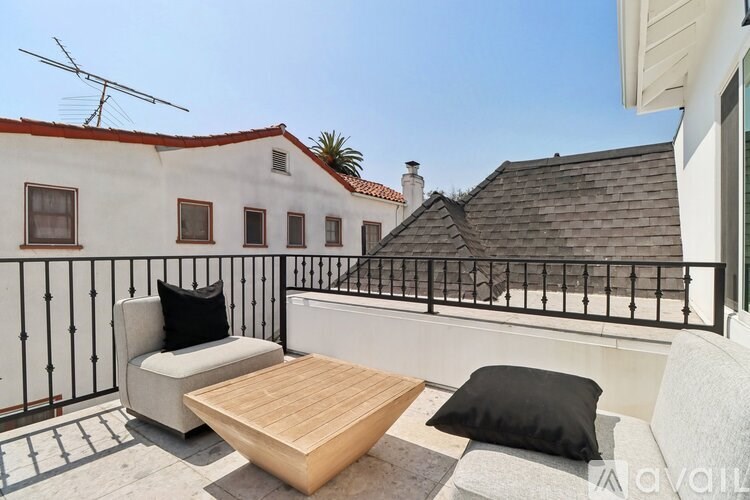 A balcony with a wooden table and two chairs with a black cushion.