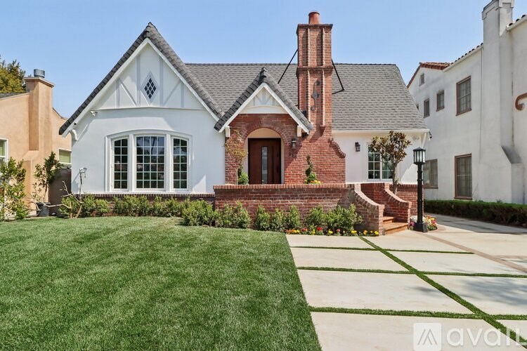A white house with a red brick chimney and a green lawn in front.