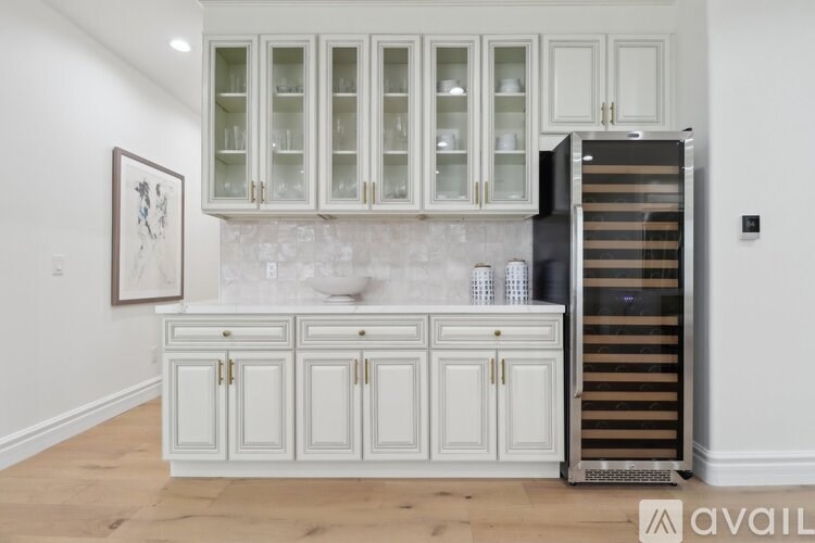 A kitchen with white cabinets and a fridge.