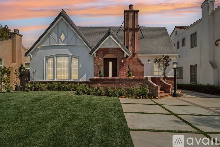 A house with a brick chimney and a grey roof is for sale.
