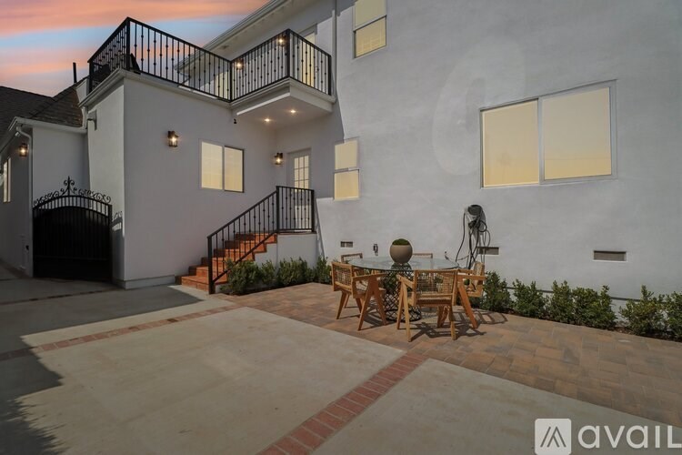 A patio with a table and chairs is in front of a house.