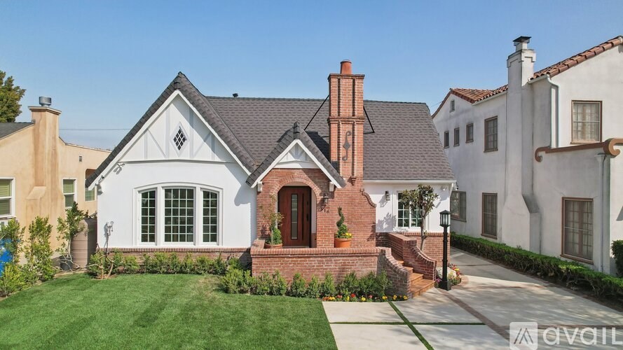 A white house with a red door and a brick chimney.
