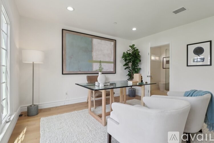 A living room with a glass table and two white chairs.