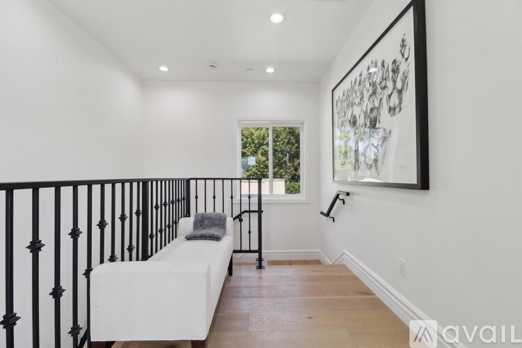 A bedroom with a white bed and a painting on the wall.
