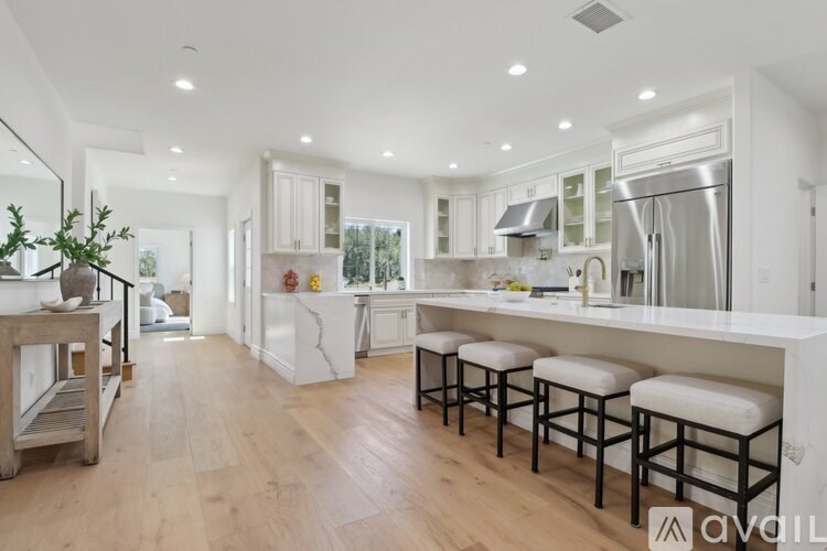 A modern kitchen with white cabinets and a wooden floor.