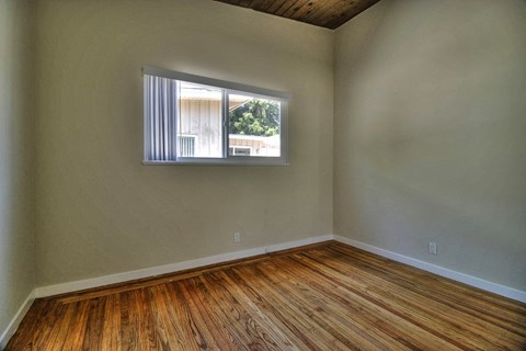 an empty living room with a window and wooden floors