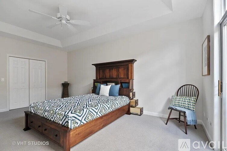 A bedroom with a bed, chair, and a ceiling fan.