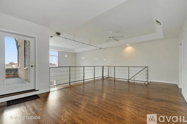 A spacious room with wooden floors and a balcony with a railing.