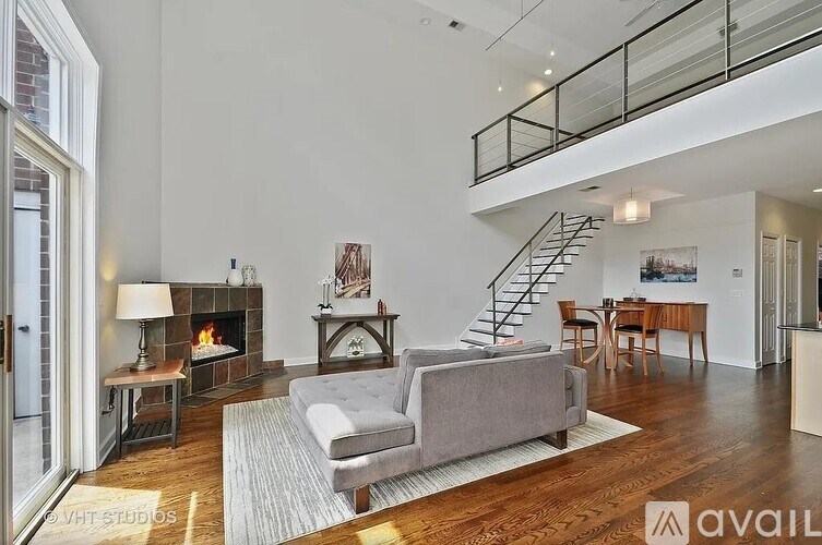 A living room with a grey couch, a fireplace, and a staircase.