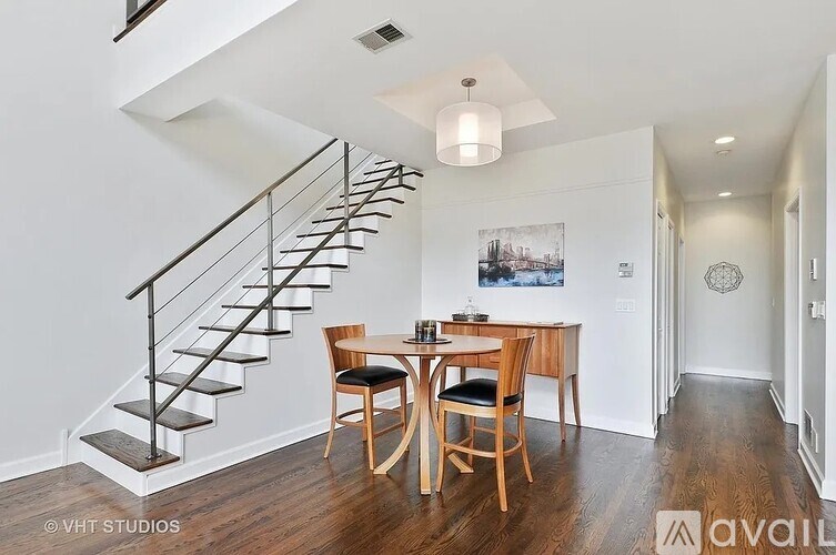 A wooden dining table with chairs is in a room with a staircase.