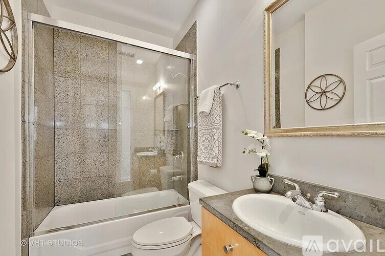 A bathroom with a white toilet, a sink, a mirror, and a glass shower stall.