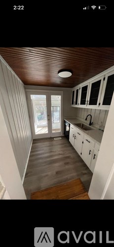 A kitchen with white cabinets and a wooden ceiling.