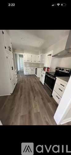 A kitchen with white cabinets and a wooden floor.