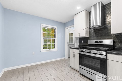 A kitchen with a stove top oven and a window with a view of a garden.
