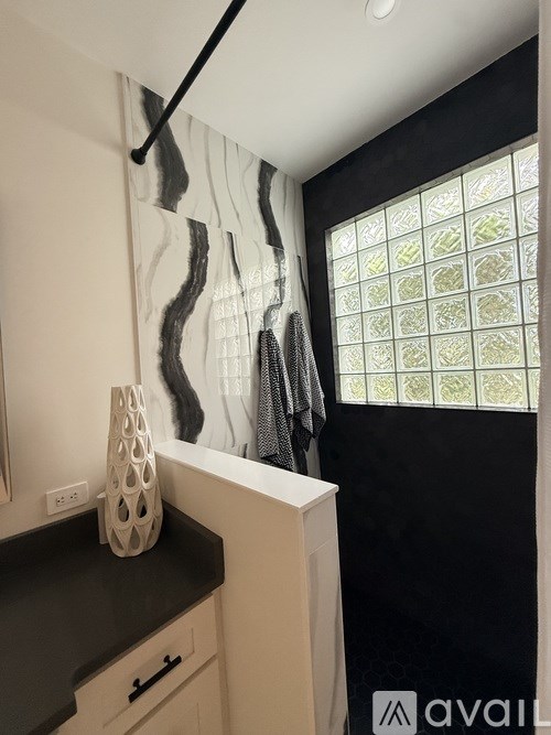 A kitchen with a black countertop and a white vase on it.