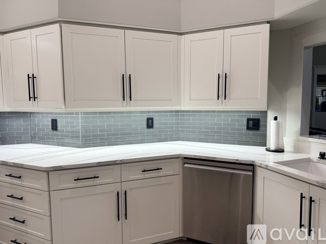 A kitchen with white cabinets and a blue tile backsplash.