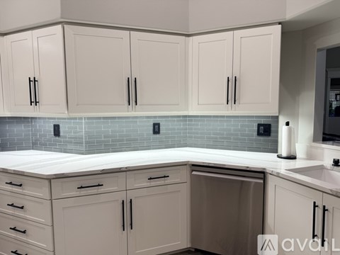 A kitchen with white cabinets and a blue tile backsplash.