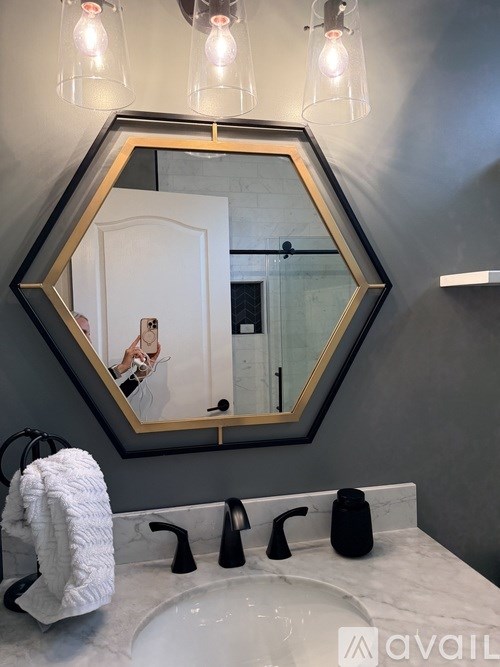 A bathroom with a white sink and a mirror with a woman's reflection in it.