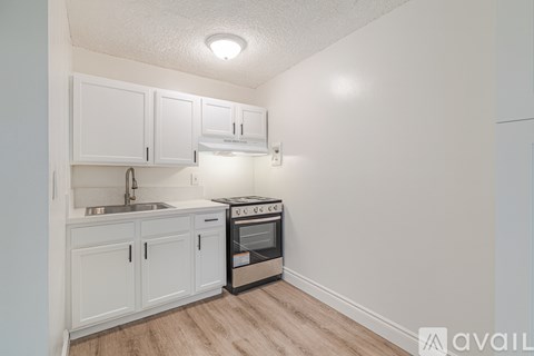 A kitchen with white cabinets and a stove top oven.