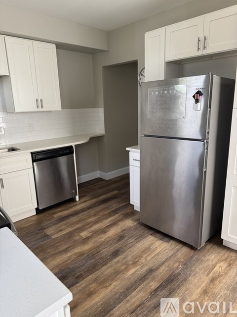 A kitchen with a stainless steel refrigerator and wooden flooring.