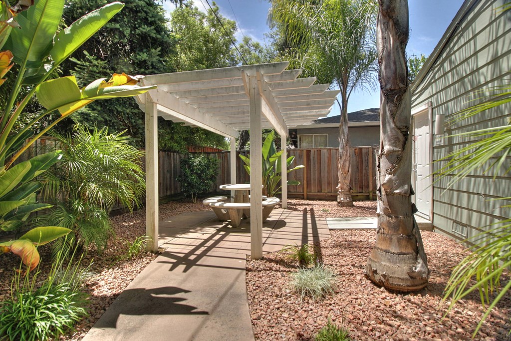 a covered patio with a table and chairs in a backyard