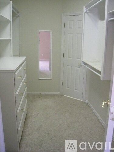 A white closet with a door and a shelf.