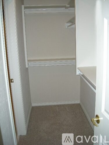 A small, empty bedroom with a carpeted floor and white walls.