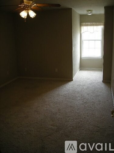 A room with a carpeted floor and a ceiling fan.