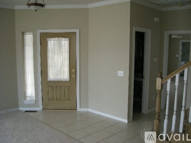 A room with a beige door and a light switch on the wall.