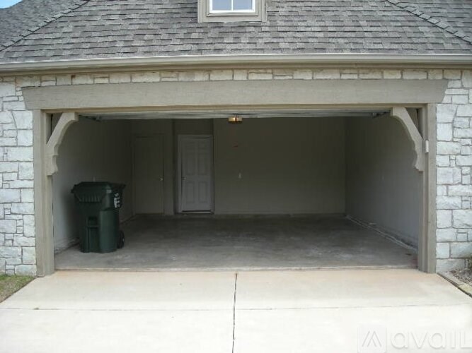 A white garage with a stone wall and a window above the door.