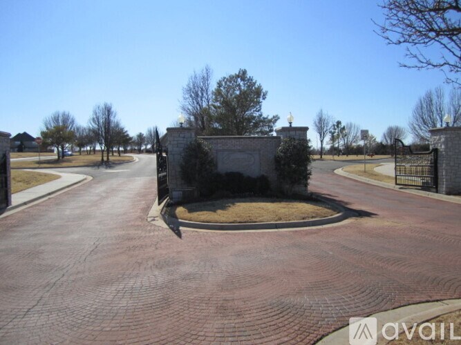 A driveway leads to a gate with a small wall and a small tree.