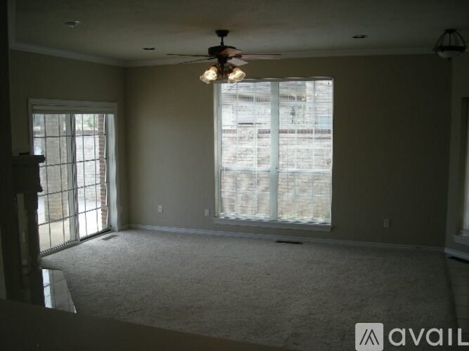 A room with a carpet floor, a ceiling fan, and a window with blinds.