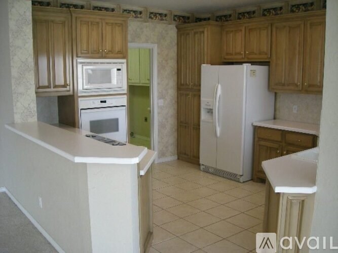A kitchen with a white fridge and wooden cabinets.