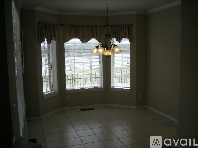 A room with a large window and a chandelier hanging from the ceiling.