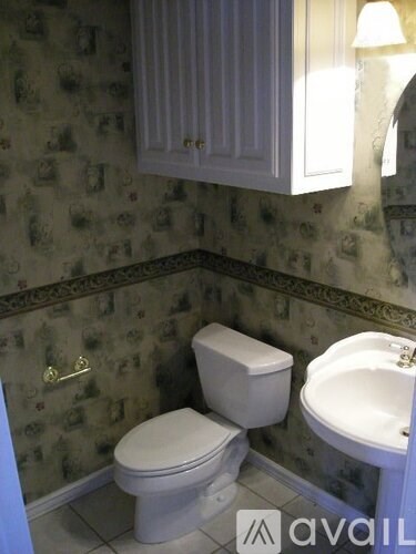 A bathroom with a toilet, sink and wallpaper.