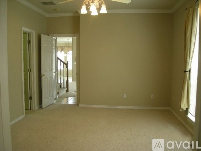 A room with beige walls and a carpeted floor with a chandelier hanging from the ceiling.