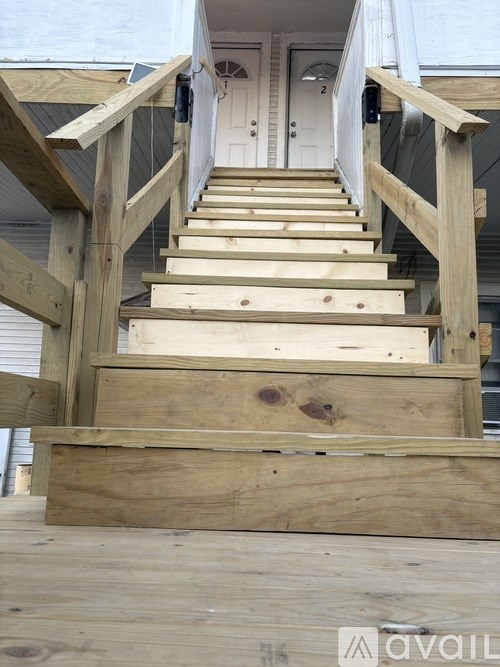 A set of wooden stairs leading to a white door.