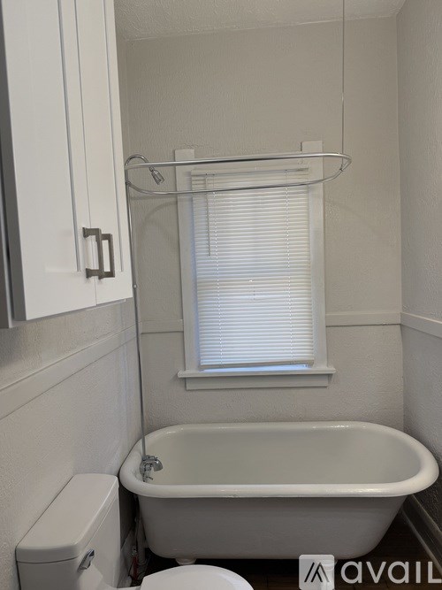 A white bathroom with a toilet, tub, and window.