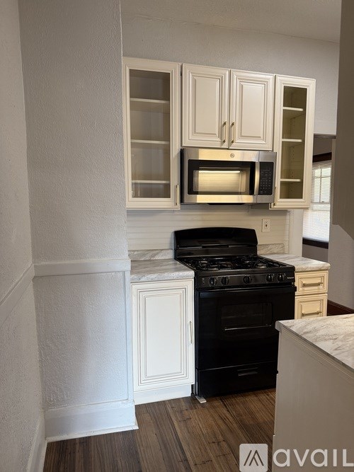 A kitchen with black appliances and white cabinets.