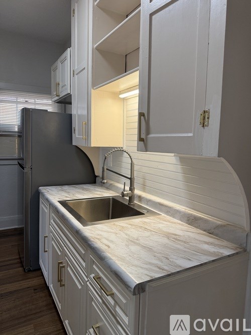 A kitchen with a marble countertop and white cabinets.