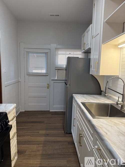 A kitchen with a refrigerator, sink, and cabinets.