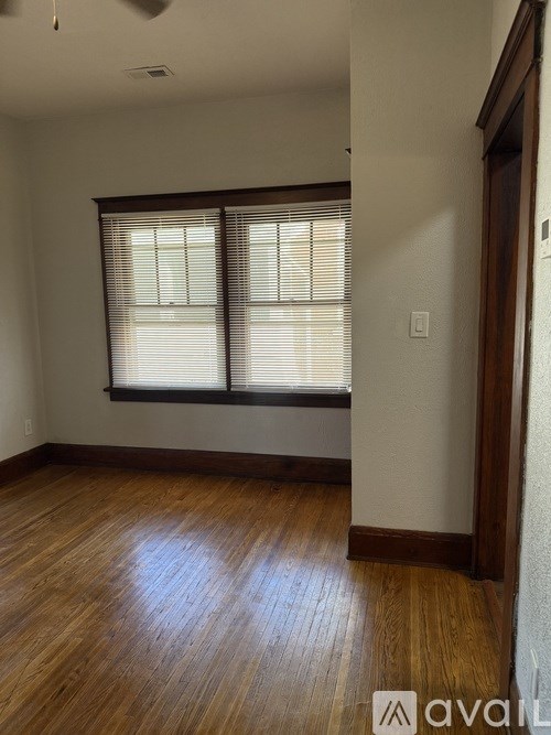 A room with wooden floors and a window with blinds.