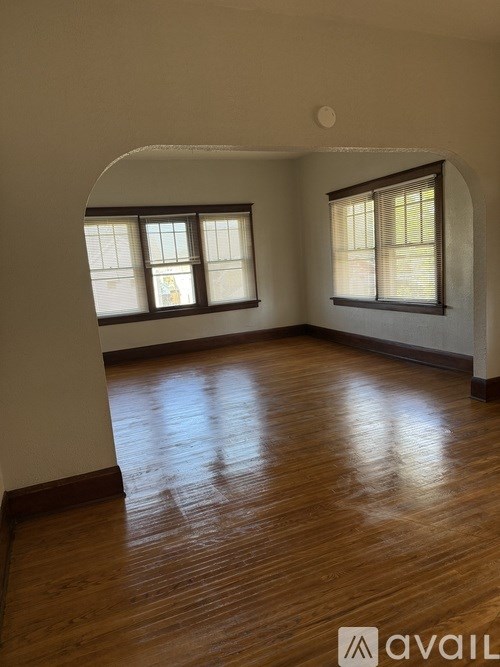 A room with wooden floors and two windows.