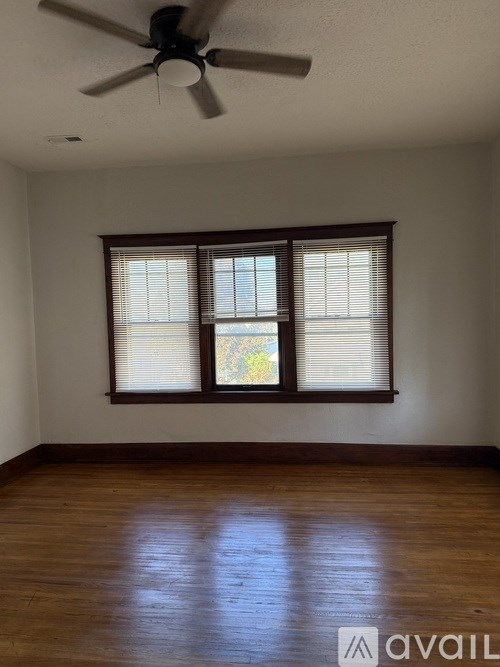 A room with a ceiling fan and a window with blinds.