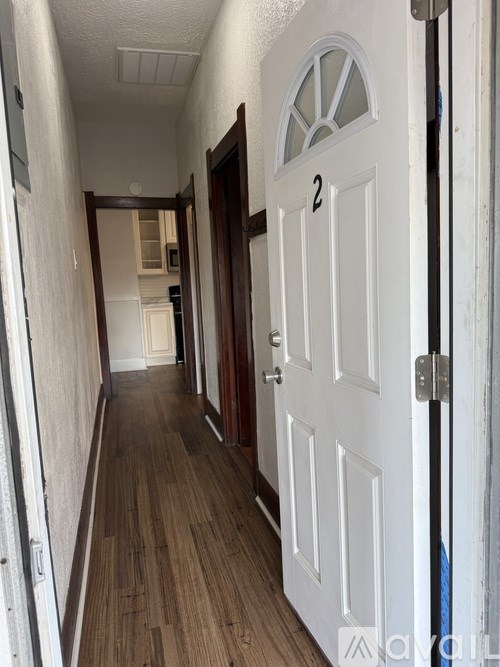 A hallway with a white door and wooden floors.